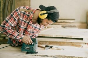 Man in Red White and Black Plaid Dress Shirt Wearing Yellow Hard Hat Holding Green Power